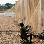 Fisherman mending his nets. Cross River, Mamfe, Cameroon. February 1965.