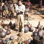 Gerald Durrell holding a black-footed mongoose among yet more calabashes full of small animals. Note the necks of the gourds plugged with local leaves to prevent the escape of the occupants.