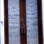 A door of the Catholic Church. The aluminium panels are made by highly skilled local craftsmen and depict a range of themes that reflect the obvious religious nature of the building. 1979.